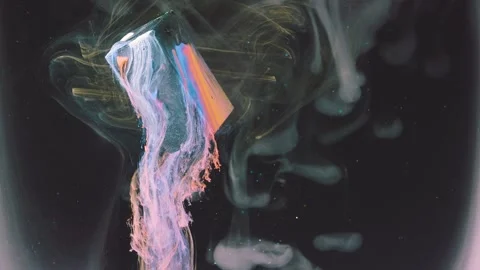 Translucent block releasing pastel ink plume in dark liquid with gold wisps and  Stock Footage 344328537
