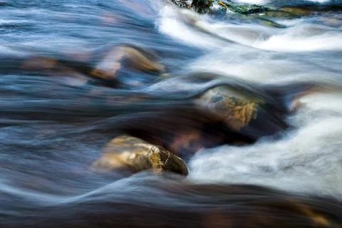 Translucent flowing river water over exposed rocks, long exposure Foto stock
