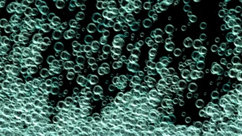 Translucent greenish-blue bubbles rise and drift in a black field Stock Footage 328482995