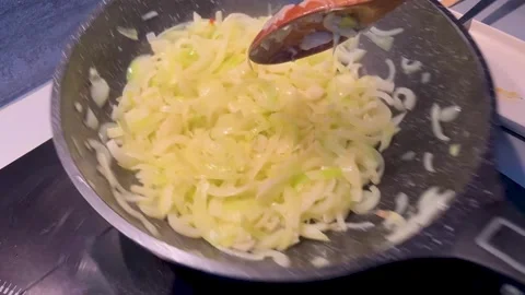 Translucent Onions Cooking In Dark Pan With Wooden Spatula 4K Stock Footage 321200910