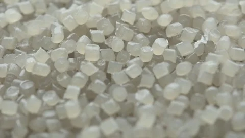 Translucent plastic pellets rotate in macro view while fresh granules fall from Stock Footage 334657543