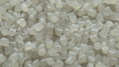 Translucent plastic pellets slowly rotate in macro view as industrial polymer Stock Footage 334657479