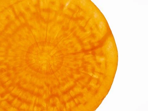Translucent slice of raw orange carrot back-lit against white background Stock Photos