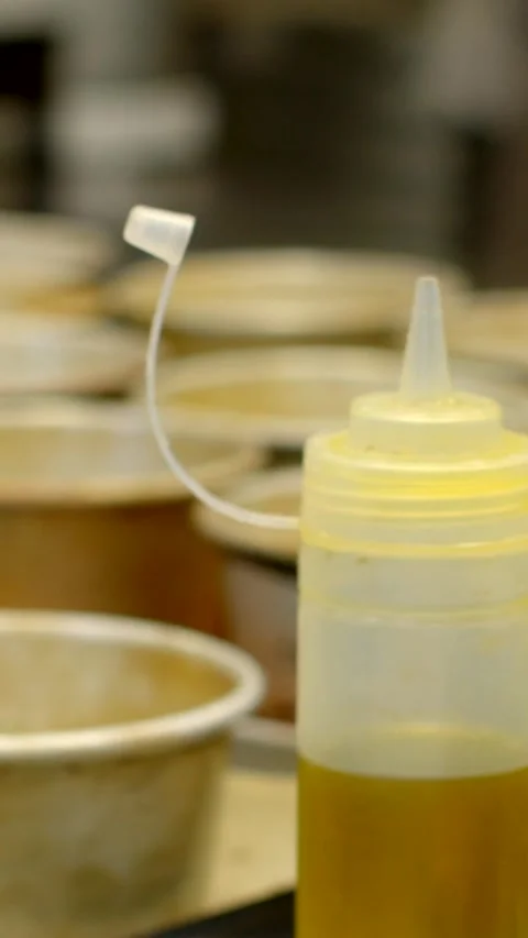 Translucent squeeze bottle with flipped cap poised for dispensing on bakery 库存影片 344570975