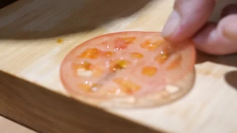 Translucent Tomato Slice Resting on a Wooden Cutting Board Stock Footage 340900675