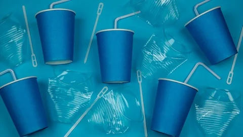 Transparent and blue plastic cups and straws fill the blue background Stock Footage 117723167
