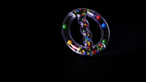 Transparent baby rattle toy spinning on black background in 8x slow motion Stock Footage