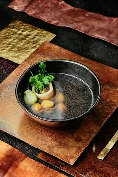 Transparent beef broth with bone, garnished with parsley and Brussels sprouts in Stock Photos