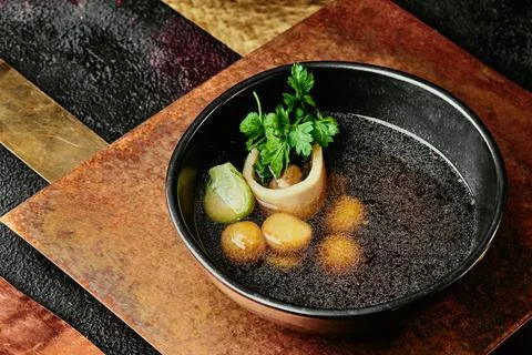Transparent beef broth with bone, garnished with parsley and Brussels sprouts in Stock Photos