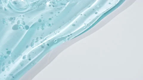 Transparent blue gel fluid with bubbles flowing down on a white surface. Macro 스톡 동영상 142999110