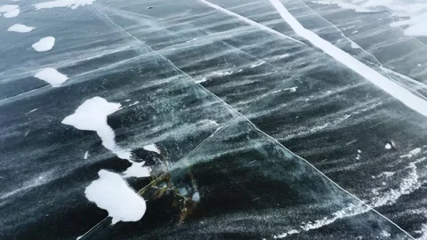 Transparent blue ice with cracks and bubbles on the frozen lake. 動画素材 298177920