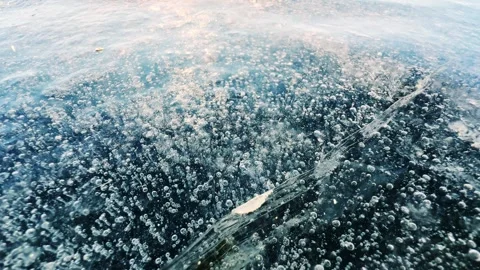 Transparent blue ice with cracks and bubbles on the frozen lake. Stockbeeldmateriaal 298178470