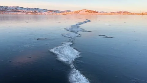 Transparent blue ice on the lake at sunset. Stockbeeldmateriaal 298178641