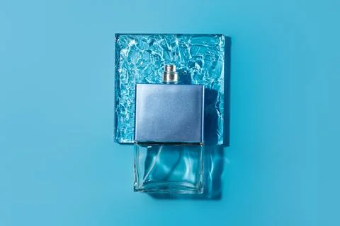 Transparent bottle of perfume on square with texture of gel blue background.. Foto stock