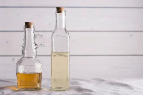 Transparent bottles with oil and vinegar on white wooden background. Stock Photos