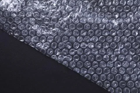 Transparent bubble wrap on black background, top view. Space for text Stock Photos