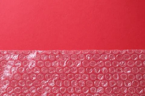 Transparent bubble wrap on red background, top view. Space for text Stock Photos