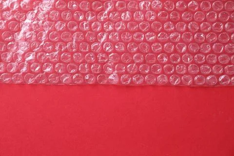 Transparent bubble wrap on red background, top view. Space for text Stock Photos