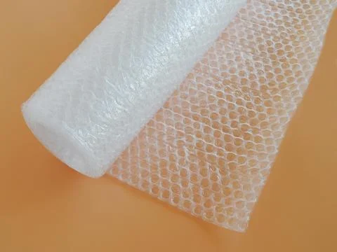 Transparent bubble wrap roll for packaging fragile items on yellow background Stock Photos