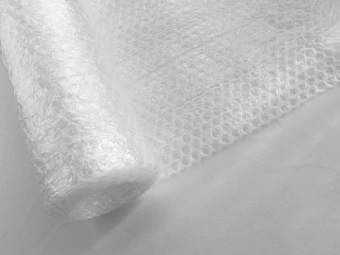 Transparent bubble wrap roll for packaging fragile items on white background Stock Photos