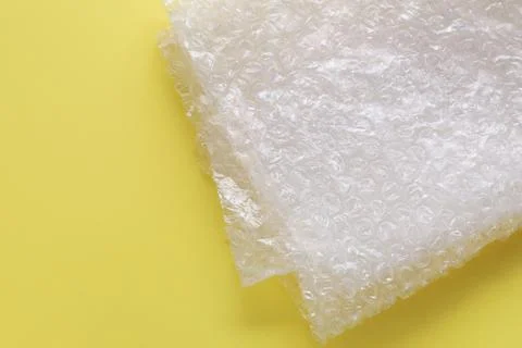 Transparent bubble wrap on yellow background, top view. Space for text Stock Photos