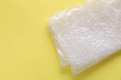 Transparent bubble wrap on yellow background, top view. Space for text Stock Photos