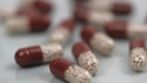 Transparent capsules with a brown cap rotate on a gray background. closeup. Stock Footage 244058938