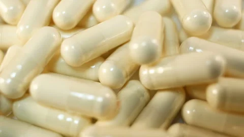 Transparent capsules with white powder inside fall on a white background. Extrem Stock Footage 144642881