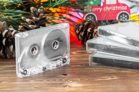 Transparent cassette tape and a stack of cases on a wooden table with a festi Stock Photos