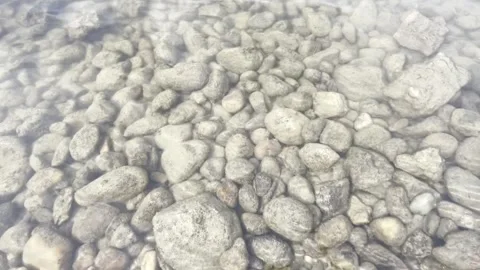 Transparent clear water waves with grey rocks at the bottom. Stock Footage 310960249