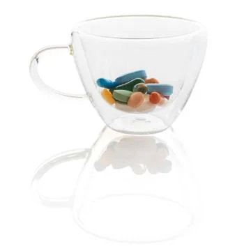 A transparent coffee cup with colourful pills Stock Photos