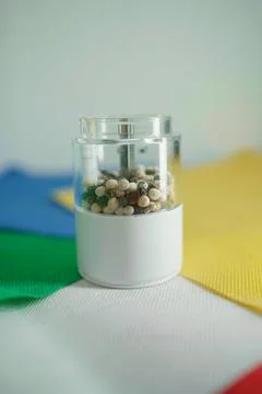 A transparent container filled with a mix of black and white peppercorns. Stock Photos