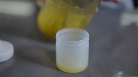 This is a transparent container filled with a yellow substance that needs to be  Stock Footage 301437139