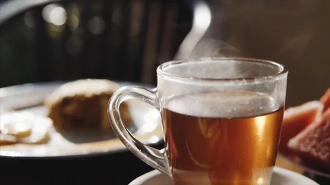 Transparent cup of hot black tea and breakfast on the blurred background on the Stock Footage 85660548