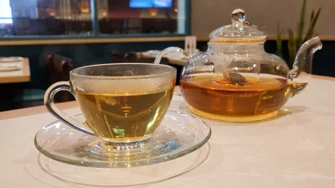 Transparent cup of hot tea. Steam rises. Teapot on table. Stock Footage 255203455