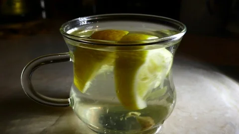 A transparent cup of lemon drink with lemon slices. Lemon water motion Stock Footage 127358562