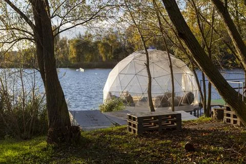 A transparent dome structure for relaxation on the river bank on a sunny au.. Stock Photos