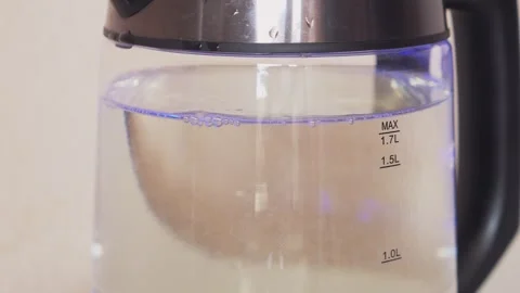 A transparent electric kettle with a blue backlight is bubbling and boiling.. Stock Footage 321439042