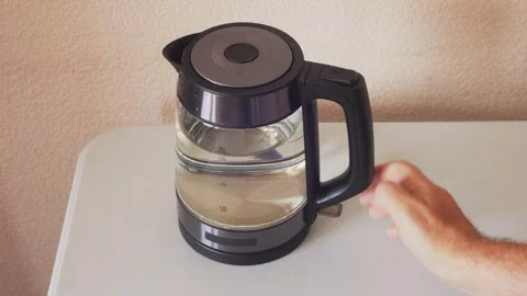 A transparent electric kettle with a blue backlight is placed on a stand, t.. Stock Footage 321439044
