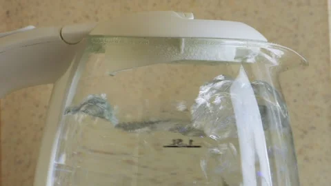 A transparent electric kettle on the table begins to boil and bubbles appea.. Vidéo 314574159