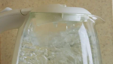 A transparent electric kettle on the table begins to boil and bubbles appea.. Vidéo 317714975