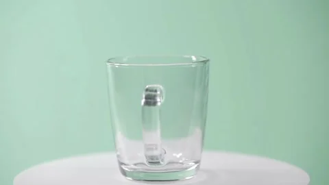 A transparent empty tea cup rotates on a green background 스톡 동영상 150449694