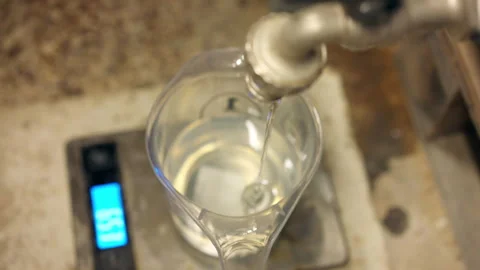 Transparent epoxy resin solution pouring into the plastic measuring cup from Stockbeeldmateriaal 265886087