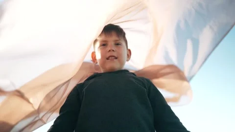 Transparent fabric flutters in the wind The child spreads his hands under the Stock-Footage 154755315