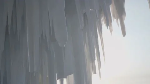 Transparent frozen sharp icicles, ice floes, winter natural landscape at sunset  Stock Footage 165663689