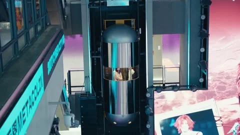 Transparent futuristic cylindrical elevator with two people inside in neon-lit Stock Footage 331229148
