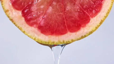 Transparent gel drop flowing down from bright red grapefruit slice Stock Footage 270479189