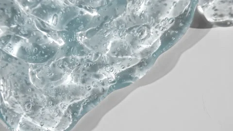 Transparent gel fluid with bubbles flowing down on a white surface. Macro Shot Vídeo Stock 142169676