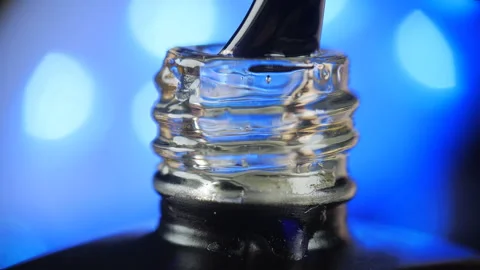 Transparent gel nail polish with an open bottle and a drop dripping into a jar Stock Footage