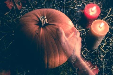 A transparent ghost hand reaching out to touch a big orange pumpkin Stock Photos